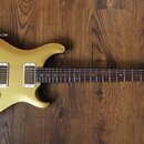 Žlutá elektrická kytara s tmavým hmatníkem a dvěma humbuckery. Na hlavě nástroje je viditelné logo Epiphone. Tělo má tři červené oválné knofíky a stř…