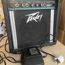 Černý přenosný kombozesilovač s logem Peavey na předním mřížkovém krytu. Horní ovládací panel obsahuje nápisy LOW Z, CHANNEL 1, MIC, CHANNEL 2, EQUAL…