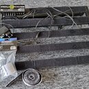 Černý kovový pedalboard s vložkami z černého plsti. Na něm je umístěn napájecí zdroj s nápisem PEDALPOWER LEWITZ a řadou výstupů. Vedle pedalboardu j…