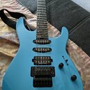 Modře lakovaná elektrická kytara s černým hardwarem a třemi snímači. Na každém ze snímačů je bílý nápis Seymour Duncan. Na hlavě hmatníku je viditeln…