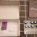 Šedý kytarový efekt s nápisem Crossfire a logem crazy tube circuits. Zařízení má pět černých ovládacích knoflíků, dva přepínače a dvě vstupní/výstupn…