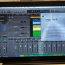 Fotografie znázorňuje otevřený notebook MacBook Pro, na jehož obrazovce je spuštěn program Logic Pro X ve verzi Version 10.0.6. V aplikaci je vidět r…