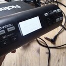 Černý elektronický perkusní modul s displejem, na kterém je nápis „Welcome to V-Drums TD-4“. Na přístroji jsou viditelná loga a nápisy „Roland“, „TD-…
