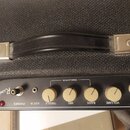 Detail ovládacího panelu černého kytarového komba s nápisem Rumble 75. Panel obsahuje čtyři béžové otočné knoflíky s popisky VOLUME, BASS, MID a TREB…