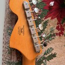 Zadní strana hlavy kytary z přírodního dřeva s chromovanými ladičkami. Na dřevě je černý nápis: Designed and Backed by Fender s/n ICS023012163 Crafte…