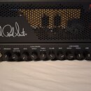 Černý kytarový zesilovač s perforovaným předním panelem. Na horní části je bílý nápis Paul Reed Smith a v pravém horním rohu červený nápis MT15. Před…