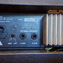 Zadní strana černého elektronického zařízení s hliníkovým chladičem. Je zde vidět napájecí konektor, přepínač GND./LIFT. a dva výjemy pro EXTERNAL SP…