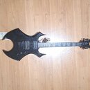 Černá elektrická kytara s atypickým, ostře hraným tvarem těla. Na hmatníku jsou viditelné bílé ornamenty a na hlavě je logo B C Rich. Kytara má dva h…