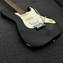 Černá elektrická kytara s bílým pickguardem a hnědým hmatníkem. Nástroj je vybaven dvěma humbuckery v pozicích u mostu a krku, jedním single-coilem u…
