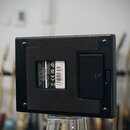 Zadní strana černého efektového pedálu s texturovaným povrchem. Na bílém štítku je uveden nápis Marshall Amplification Plc, Denbury, Romford, Essex,…