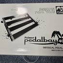 Bílá papírová krabice s černými nápisy a grafikou. Na povrchu je obrázek pedalboardu a texty „DEFINE YOUR TONE“, logo „Palmer Musical Instruments“ a…