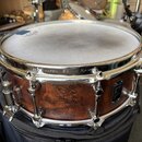 Kytarový snare drum s dřevěným korpusem v hnědé barvě s výraznou masivní strukturou zrna. Na chromovaném obruči je vyražen nápis MAFEX SONIC SAVER. N…