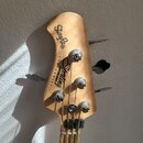 Hlava basové kytary z přírodního dřeva s nápisy StingRay a Sterling SUB SERIES by MUSIC MAN. Na hlavě jsou umístěny čtyři chromované ladičky s kovový…
