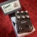 Kytarový pedál v černé barvě s nápisem Dream 65 REVERB-AMP a logem Universal Audio. Zařízení má pět ovládacích knoflíků, přepínač BOOST a dva spínací…