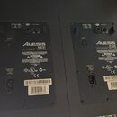 Zadní strany dvou černých studiových monitorů značky Alesis s nápisem M1 ACTIVE REFERENCE MONITOR. Jsou vidět konektory pro audio vstup, regulace Inp…