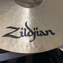 Detailní záběr na povrch mosazného činely s viditelným broušením. Uprostřed je černý nápis Zildjian s registracní značkou ®. Povrch vykazuje drobné š…