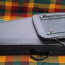 Černý pol pevný pouzdro na hudební nástroj s rukojetí. Na povrchu je bílý obdélníkový štítek s červeným nápisem GIGBAG CASES. V horní části je připev…