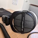Černé otevřené sluchátka s kroužkovým kabelem. Na vnější straně mušle je bílý nápis DT 990 PRO 250 OHM. Povrch sluchátek vykazuje mírné opotřebení a…