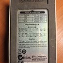 Zadní strana šedého efektpedálu značky BOSS. Na přístroji je nalepený bílý štítek s tabulkou pro BOSS AC ADAPTOR, informacemi o napájení Dry battery…