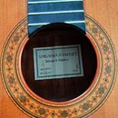 Detail kytary s viditelným otvorem rezonanční skříně a částí hmatníku. Uvnitř otvoru je štítek s nápisy „ANTONIO SANCHEZ“, „Artesano de Guitarras“, „…