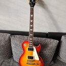 Elektrická kytara s tvarem Les Paul v červeno-žlutém sunburst provedení. Na hlavě hředu je bílý nápis Harley Benton a v dolní části logotyp s písmene…