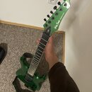 Zelená elektrická kytara s kovovými strunami a černým hmatníkem. Na hlavě je bílý nápis Harley Benton a Programmable Series. Tělo i hlava mají kovový…