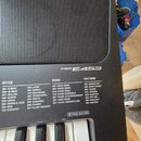 Detailní záběr na černý digitální klavír s nápisem PSR-E453. Pod názvem modelu se nachází tabulky s přepsky seznamy kategorií STYLE, SONG a PATTERN.…