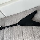 Zadní strana černé elektrické kytary s tělem ve tvaru V. Na hlavě je viditelné logo "Epiphone". Povrch nástroje je matný a v dobrém stavu.
