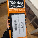 Kartonová krabička oranžové barvy s nápisem Tube Amp Doctor™ a SELECTED TUBES PREMIUM QUALITY. Na boku je bílá nálepka s textem RT834, TAD 6V6GT-STR…
