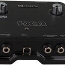 Černý audio rozhraní s nápisem UX1 a logem LINE 6. Na horní straně jsou dvě stříbrné otočné kontrolky a nápisy PHONES, INSTRUMENT a MIC. V zadní část…