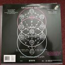 Zadní strana vinylové desky s černým pozadím a bílým grafickým motivem složeného z kruhů, symbolů a nápisů. V horní části jsou seznamy skladek: vlevo…