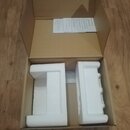 Otevřený hnědý karton, ve kterém jsou dva bílé polystyrenové tvarovky. Uvnitř krabice leží papírový návod s nápisem HEALIGHT. Povrchy krabice a polys…