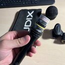Černý dynamický mikrofon s nápisem AUDIX OM-3xb. Horní část mikrofonu je bez mřížky, viditelná je kapsle s bílou nálepkou, na které je čitelně text D…