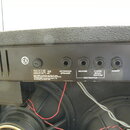 Zadní panel kytarového komba s černým povrchem. Jsou zde vidět čtyři vstupy s nápisy EXTENSION SPEAKER, REVERB, CLEAN/SOLO/RHYTHM a INSERT, dále nápi…