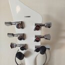 Zadní strana bílé kytarové hlavy s šesti chromovanými ladičkami. Na každém ladičku je vyryto logo GOTOH a nápis MADE IN JAPAN. V horní části hlavy je…