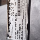Detailní záběr na bílý štítek s technickými specifikacemi nalepený na černém povrchu. Na štítku je svisle napsáno Octagonheater a STAIRVILLE, dále úd…