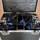 Otevřený transportní kufr s pěnovou výplní v lidech, který obsahuje svazek černých kabelů s modrými konektory a dvě černé elektronické jednotky. Na p…