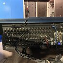 Zadní strana tmavě modrého digitálního mixážního pultu s velkým množstvím zapojených kabelů. Na zadním panelu jsou viditelné nápisy LF048 a logo digi…