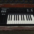 Černý MIDI kontrolér s klaviaturní klávesou. Na horním panelu je nápis KOMPLETE KONTROL S25 a v pravém horním rohu označení MK1. Zařízení obsahuje ně…