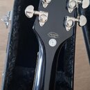 Zadní strana černé kytarové hlavy s chromovanými ladičkami. Na zadní straně je nalepená bílá oválná nálepka s nápisem HAND-CRAFTED IN CHINA a pod ní…
