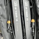 Dvě černé svítící lišty s nápisem eurolite LED IP T-BAR 16 qCL Outdoor Bar. Jsou umístěny v černé přepravní tašce a mají připojené napájecí kabely s…