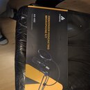 Černá krabice s žlutými prvky, na které je zobrazen mikrofonní set. Na obalu jsou bílé nápisy maono, CONDENSER PODCASTING MICROPHONE KIT a AU-A03 Pro…