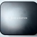Černý obdélníkový box se zaoblenými rohy a matným povrchem. Uprostřed je bílý nápis BANG & OLUFSEN. Povrch vykazuje mírné odrazy světla.