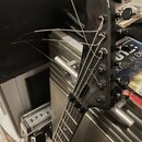 Černá hlava elektrické kytary s šesti ladicími kolíky. Struny jsou pouze navaženy, konce jsou volně nataženy do strany. Na hlavě nejsou viditelné žád…