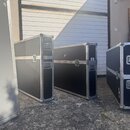 Tři černé transportní kufry s kovovými hranami a rohy. Kufry mají kovové zámky a madla, povrch vykazuje známky běžného používání v podobě drobných od…