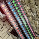 Čtyři černé lineární LED osvětlovací panely s různými barvami diod (červené, modré a zelené). Panely jsou umístěny vedle sebe na kovovém flightcasu u…