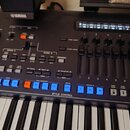 Černý digitální klavír s bílými a černými klávesami. Na ovládacím panelu je viditelné logo YAMAHA, řada posuvníků s čísly 1 až 8 a modrá tlačítka v s…