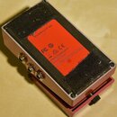 Zadní strana efektového pedálu v červené barvě. Na spodní straně je oranžová nálepka s nápisy „Dry battery 9 V type“, „FC“, „CE“ a „BOSS Corporation…