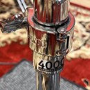 Detail chromovaného kovového spojovacího mechanismu stojanu. Na povrchu je vyryt nápis MUNOR a níže se nachází štítek s textem 4000 HARDWARE SERIES.…