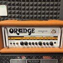 Kytarový zesilovač v oranžovém vinylu s bílým předním panelem. Na panelu je velký nápis ORANGE a modelové označení ROCKERVERB 50. Zesilovač má ovláda…